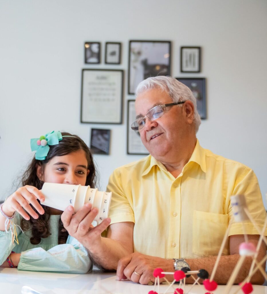 Grandfather enjoying a playful moment with his grandchildren indoors, fostering bonding and learning.