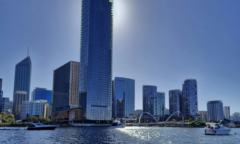 Stunning view of Perth skyline with sunlit skyscrapers reflecting on the Swan River.