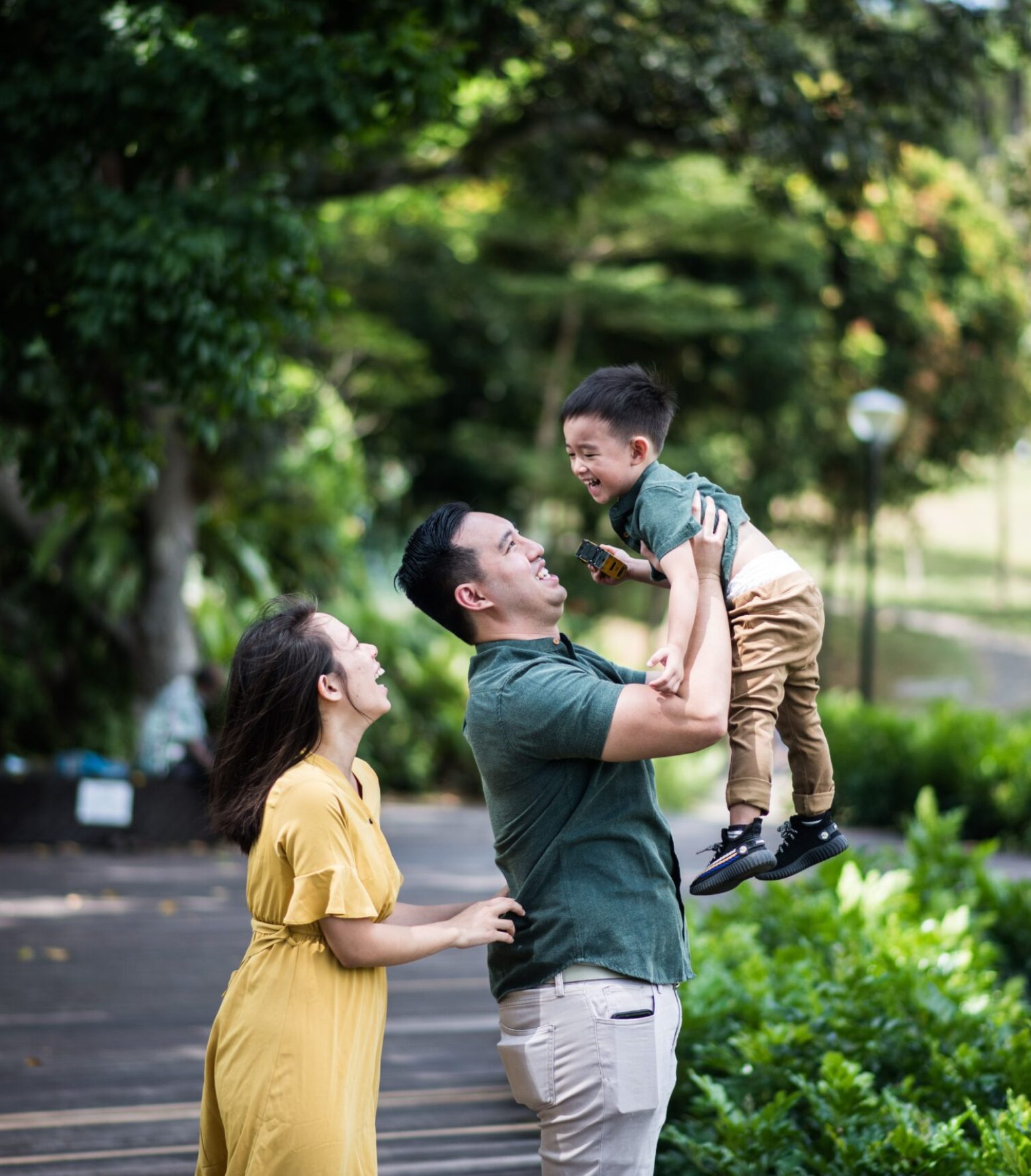 Joyful family bonding moment in a lush Singapore park setting, capturing laughter and love.