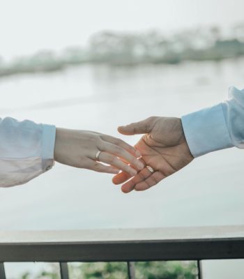 A couple gently reaching for each other's hands, symbolizing love and connection.