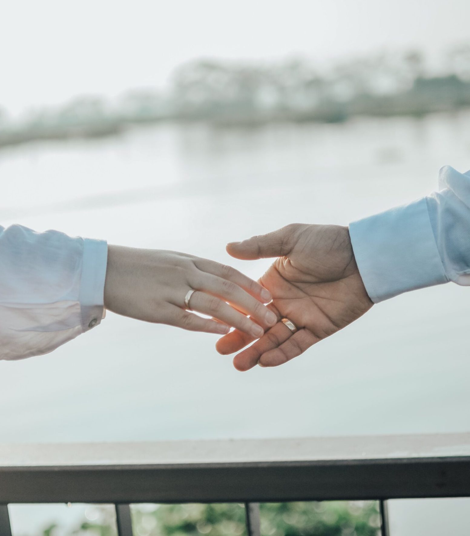 A couple gently reaching for each other's hands, symbolizing love and connection.