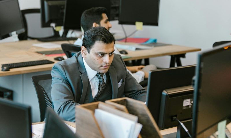 A dedicated businessman in a suit concentrating on work at a modern office desk.