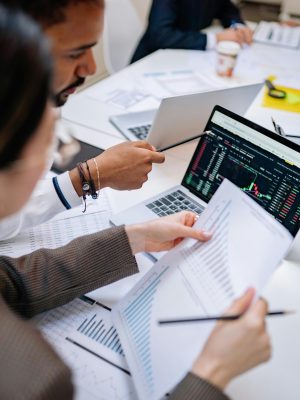 Team collaborating with laptops and documents in an office setting, analyzing data.