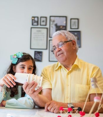 Grandfather enjoying a playful moment with his grandchildren indoors, fostering bonding and learning.